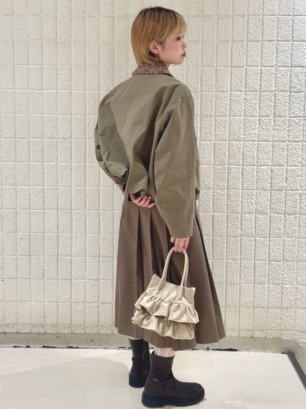 グリーン系のブルゾン、ブラウン系のスカート、ベージュ系のハンドバッグを着用したレディースの冬コーディネートの3枚目の写真