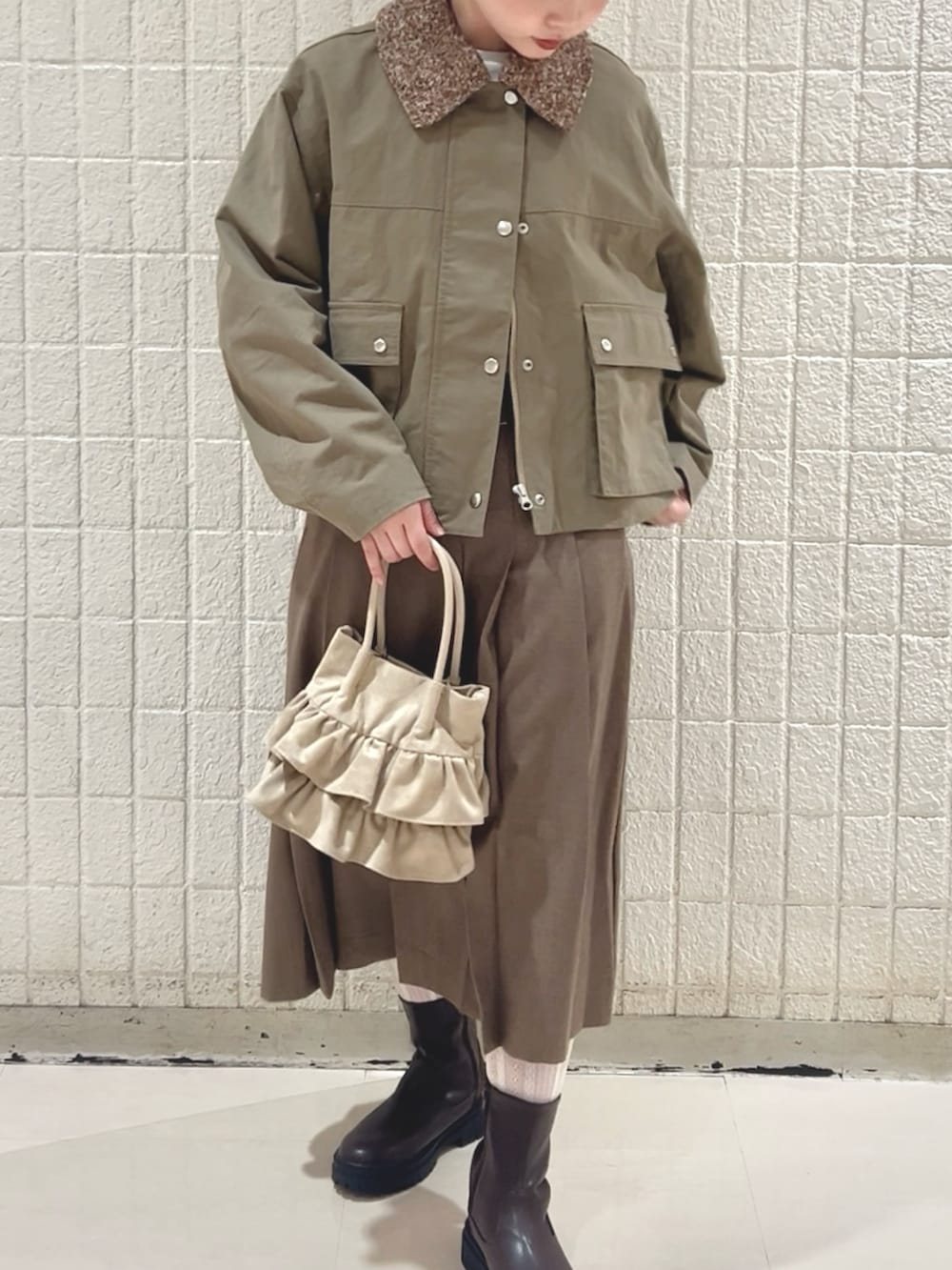 グリーン系のブルゾン、ブラウン系のスカート、ベージュ系のハンドバッグを着用したレディースの冬コーディネートの2枚目の写真