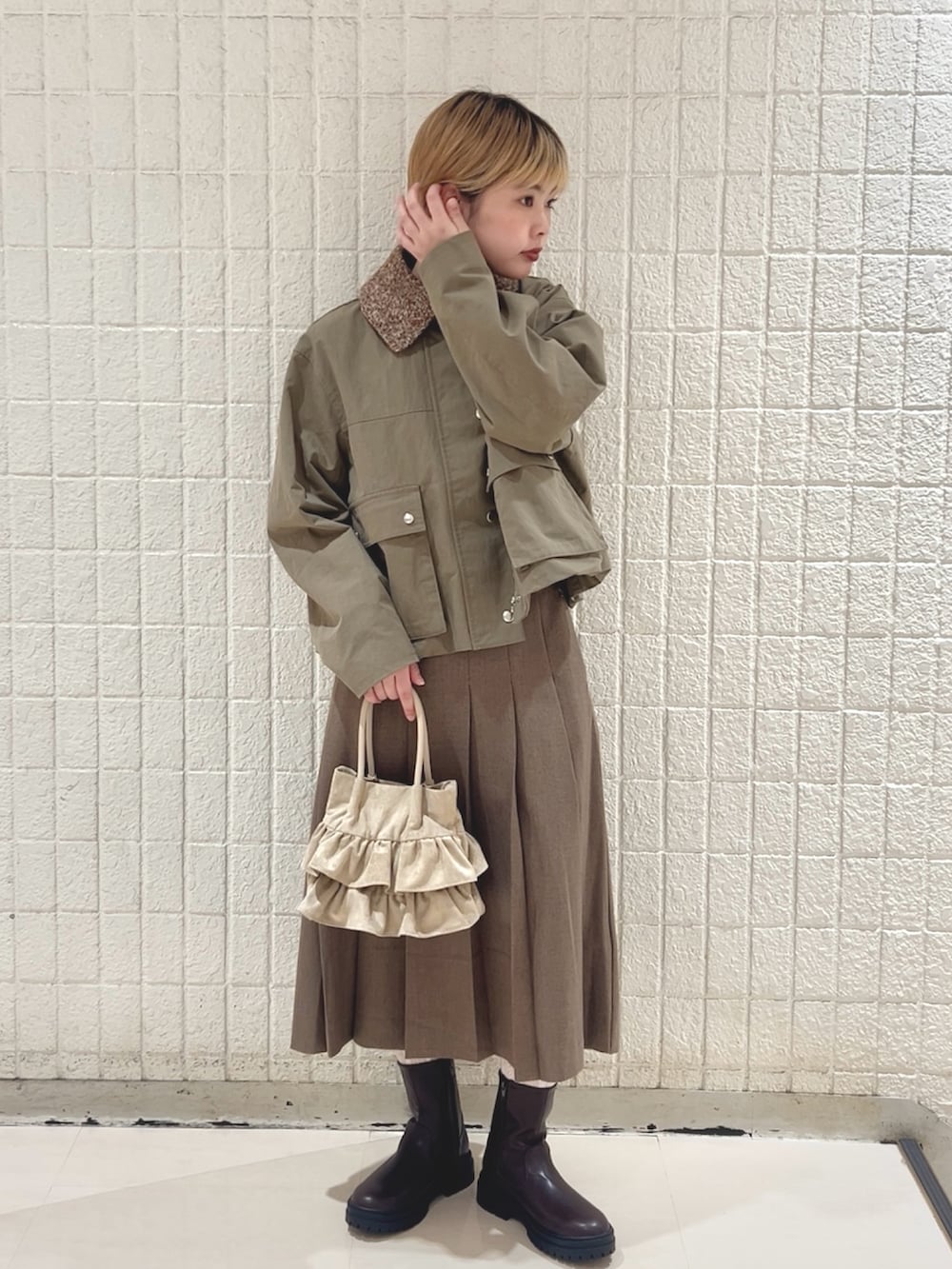 グリーン系のブルゾン、ブラウン系のスカート、ベージュ系のハンドバッグを着用したレディースの冬コーディネートの4枚目の写真