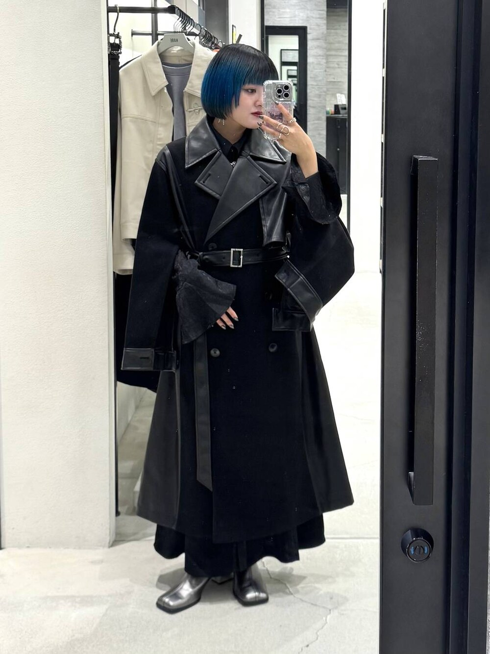 ブラック系のチェスターコート、シルバー系のブーツ、ブラック系のワンピースを着用したレディースの秋コーディネートの2枚目の写真