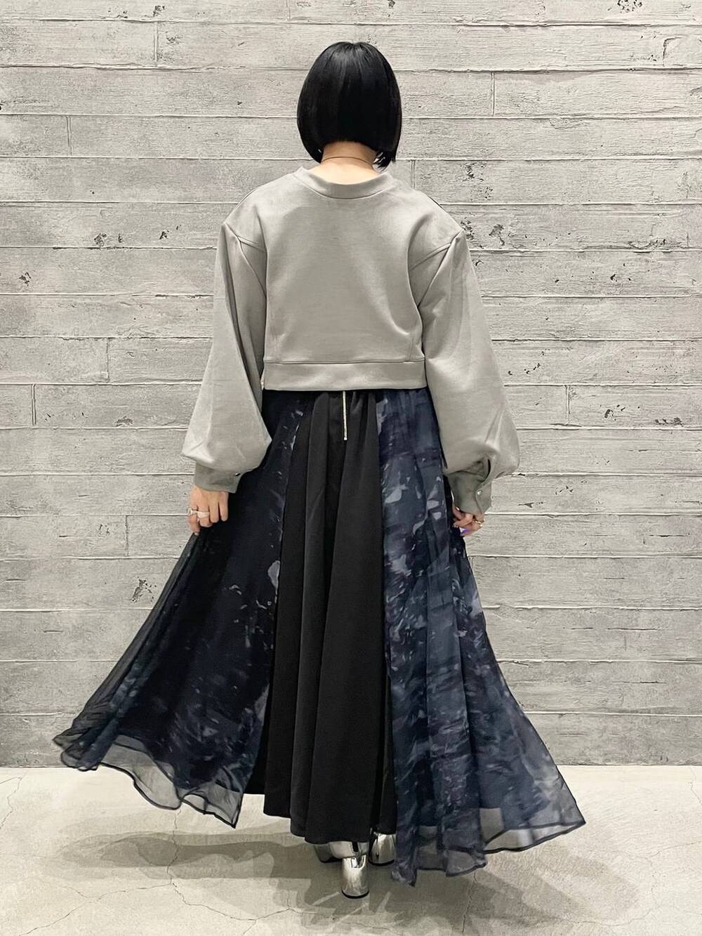 シルバー系のブーツ、ブルー系のスカート、グレー系のスウェットを着用したレディースの秋コーディネートの4枚目の写真
