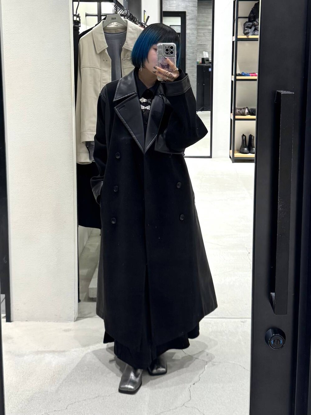 ブラック系のチェスターコート、シルバー系のブーツ、ブラック系のワンピースを着用したレディースの秋コーディネートの5枚目の写真