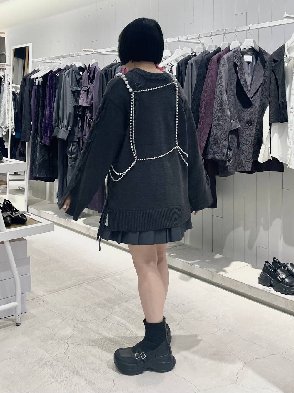 グレー系のテーラードジャケット、ブラック系のブーツ、グレー系のニット/セーターを着用したレディースの秋コーディネートの4枚目の写真