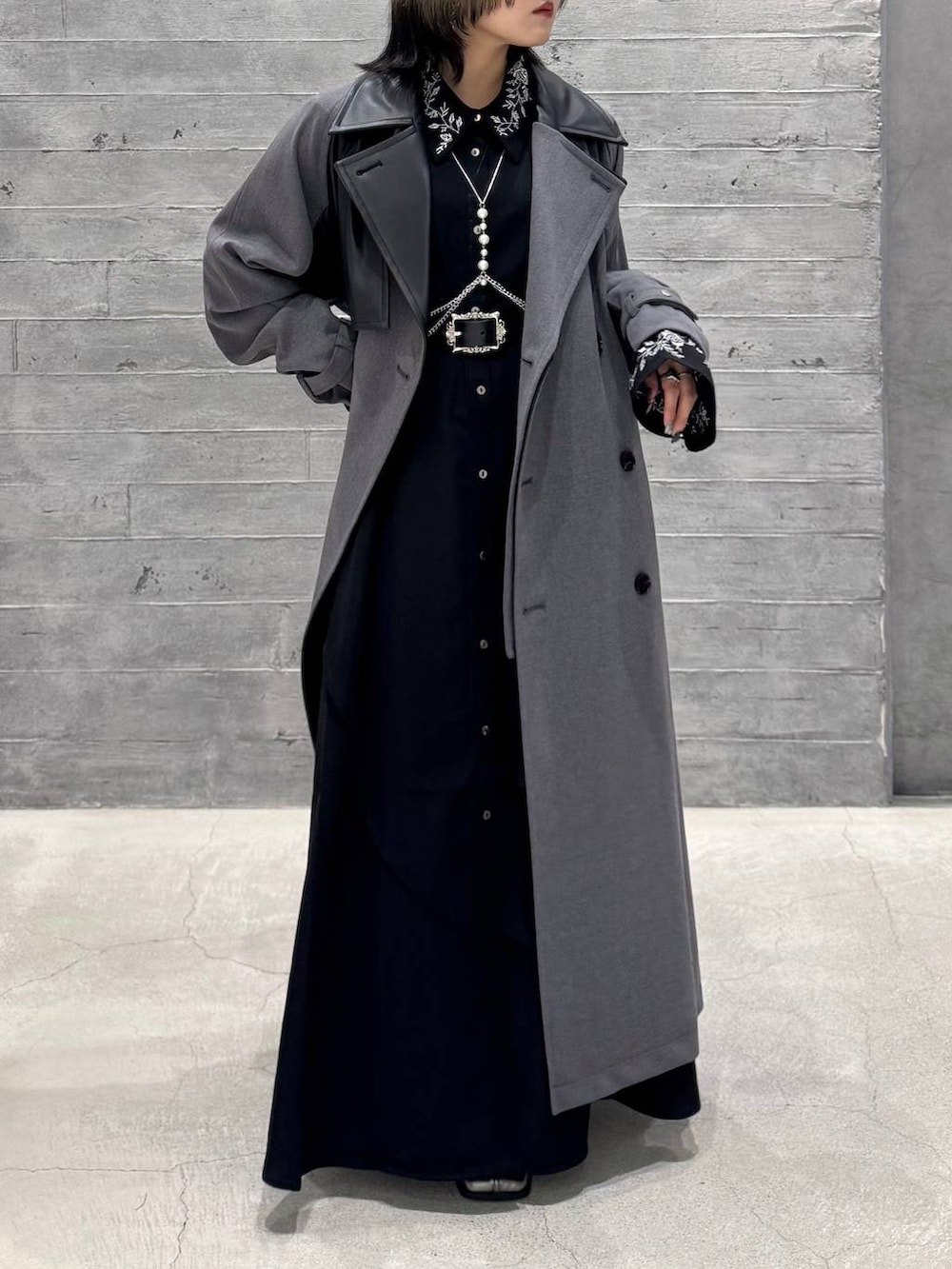 シルバー系のブーツ、グレー系のトレンチコート、ブラック系のワンピースを着用したレディースの秋コーディネートの2枚目の写真