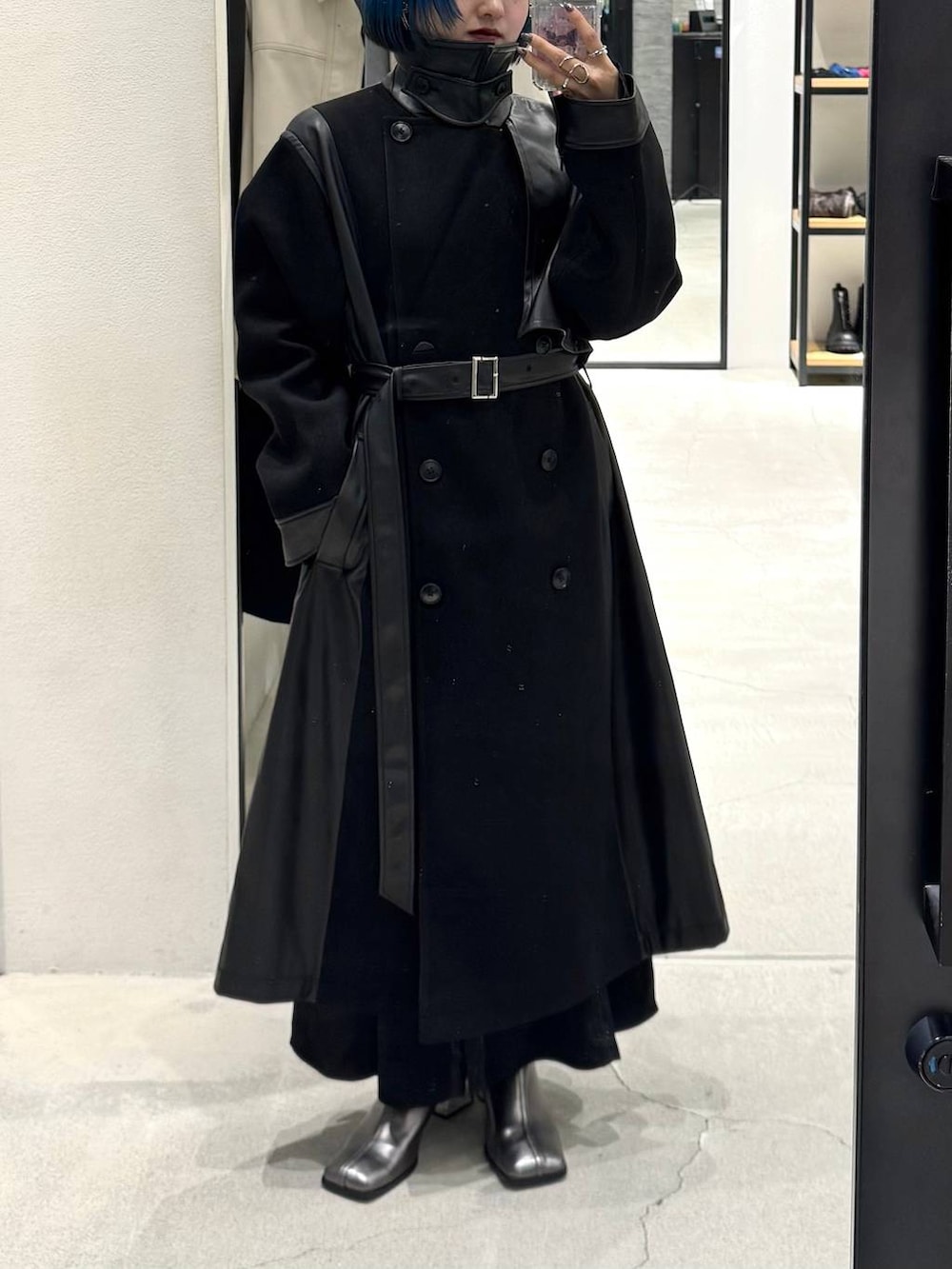 ブラック系のチェスターコート、シルバー系のブーツ、ブラック系のワンピースを着用したレディースの秋コーディネートの4枚目の写真