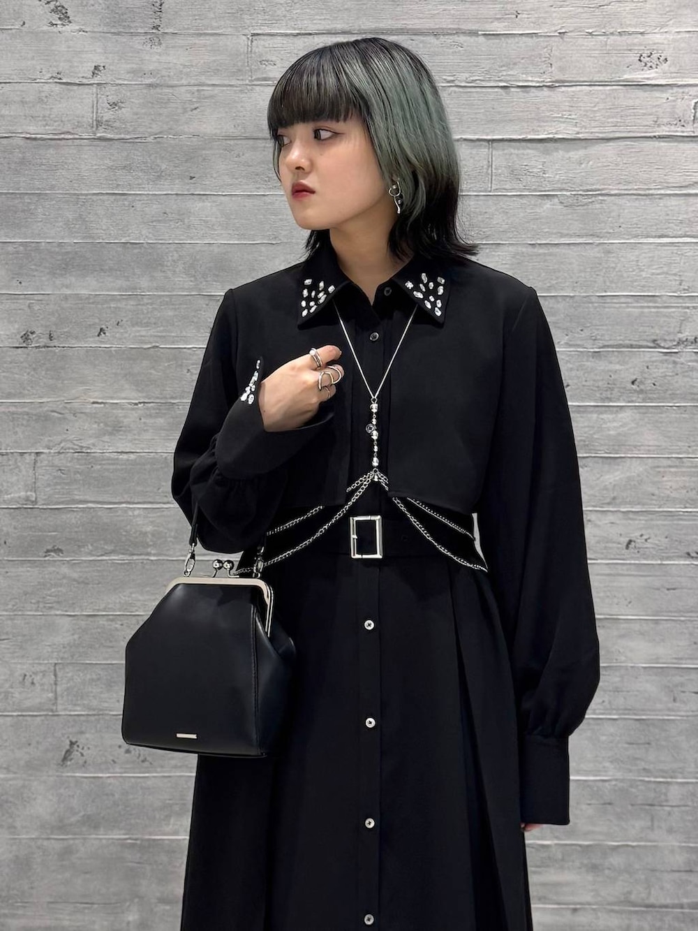 シルバー系のブーツ、ブラック系のワンピース、ブラック系のショルダーバッグを着用したレディースの秋コーディネートの2枚目の写真