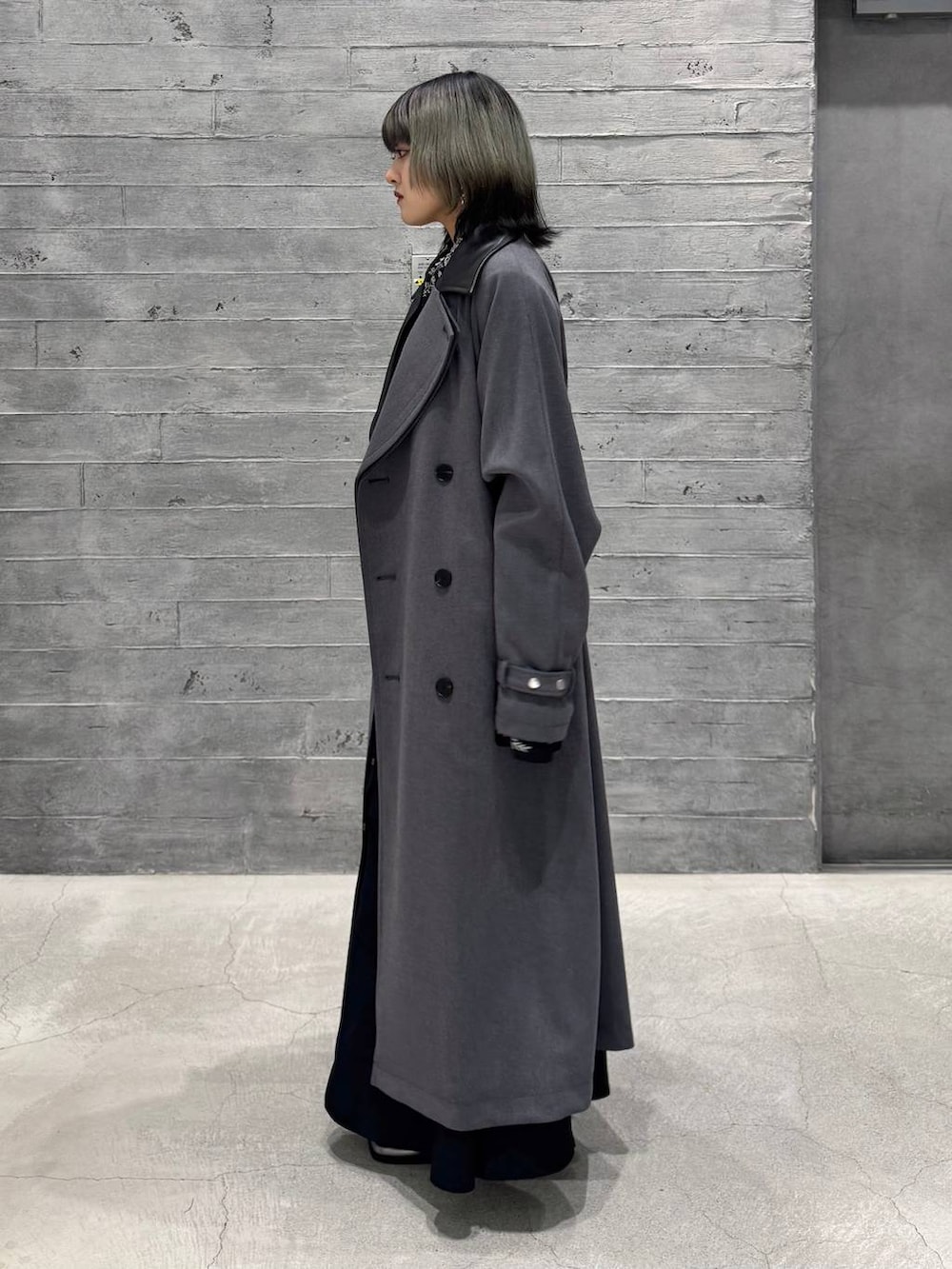 シルバー系のブーツ、グレー系のトレンチコート、ブラック系のワンピースを着用したレディースの秋コーディネートの3枚目の写真