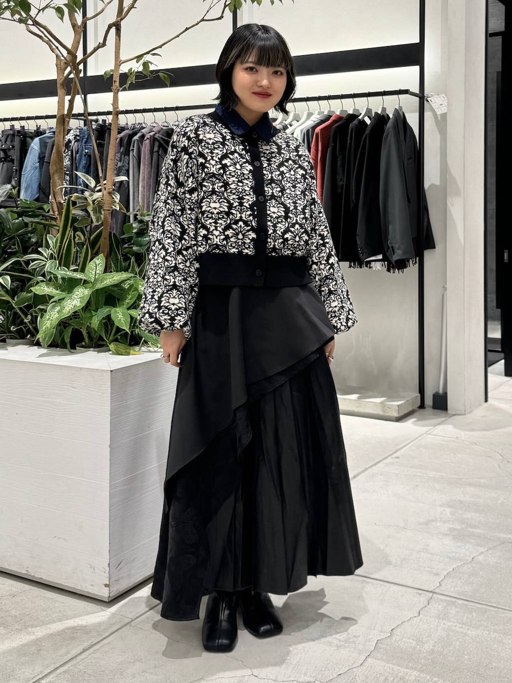 ブラック系のスカート、ブラック系のブーツ、ブラック系のニット/セーターを着用したレディースの秋コーディネートの2枚目の写真