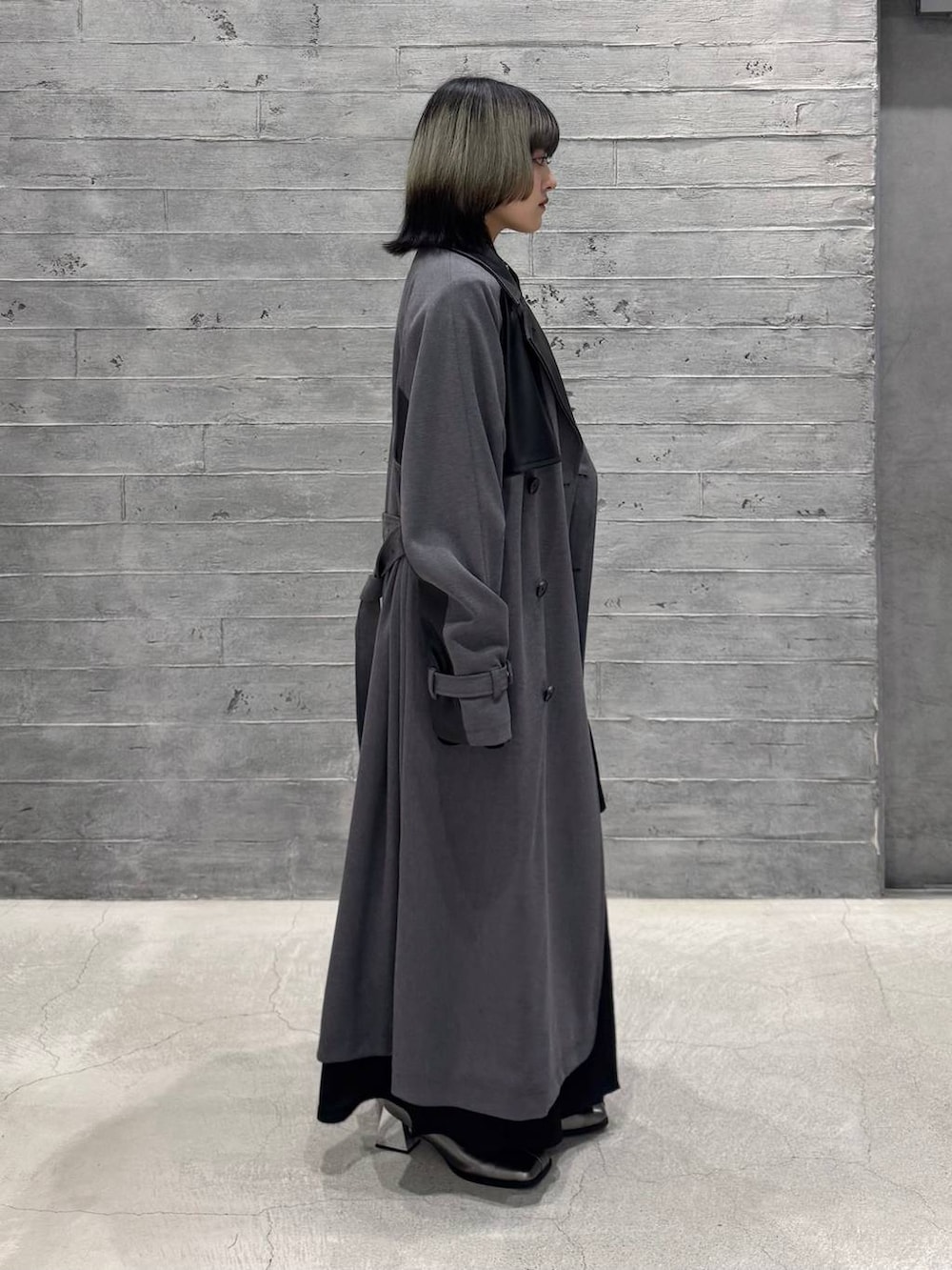 シルバー系のブーツ、グレー系のトレンチコート、ブラック系のワンピースを着用したレディースの秋コーディネートの5枚目の写真