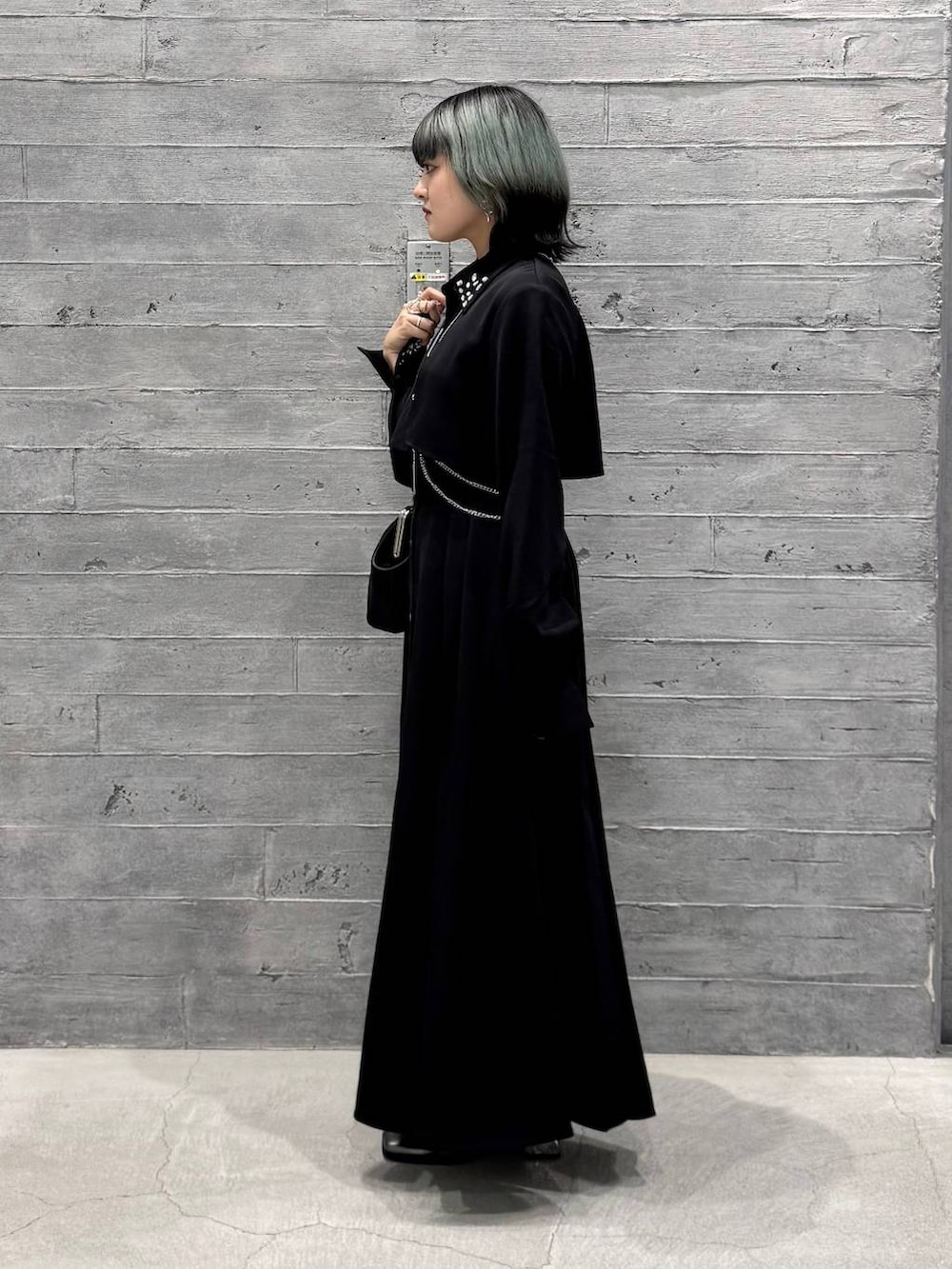 シルバー系のブーツ、ブラック系のワンピース、ブラック系のショルダーバッグを着用したレディースの秋コーディネートの4枚目の写真