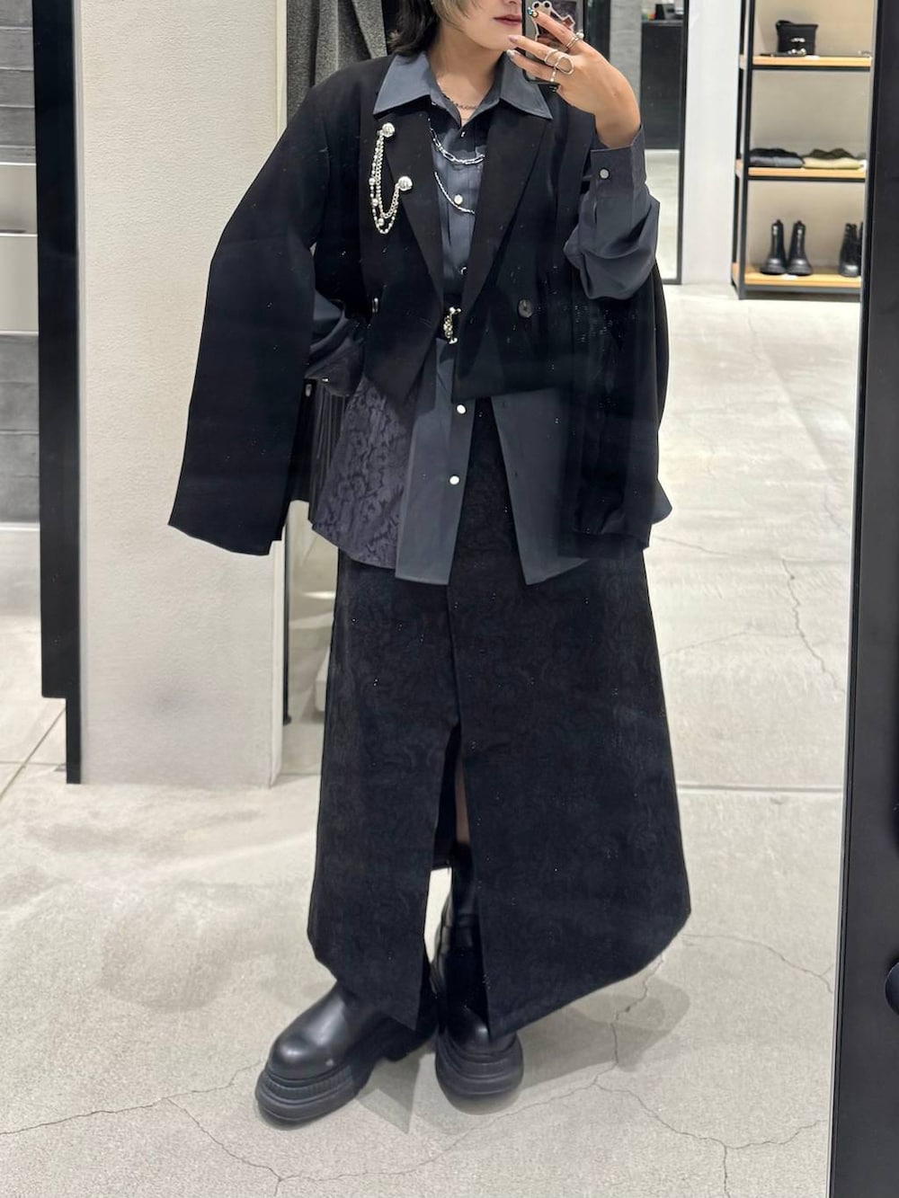 ブラック系のブーツ、ブラック系のテーラードジャケット、ブラック系のスカートを着用したレディースの秋コーディネートの2枚目の写真