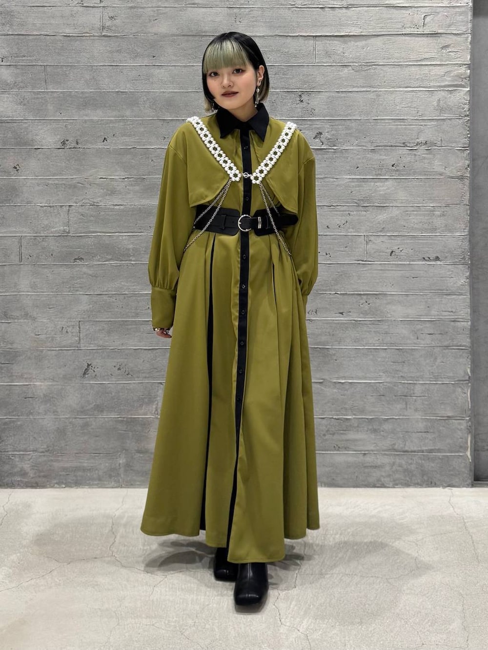 グレー系のブルゾン、ブラック系のブーツ、イエロー系のワンピースを着用したレディースの冬コーディネートの2枚目の写真