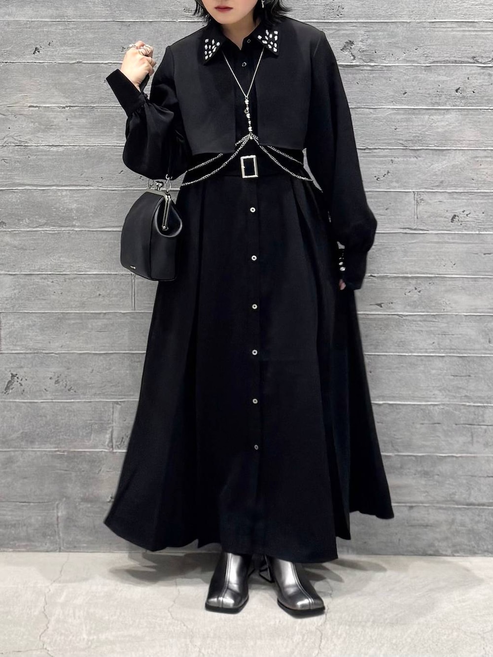 シルバー系のブーツ、ブラック系のワンピース、ブラック系のショルダーバッグを着用したレディースの秋コーディネートの3枚目の写真