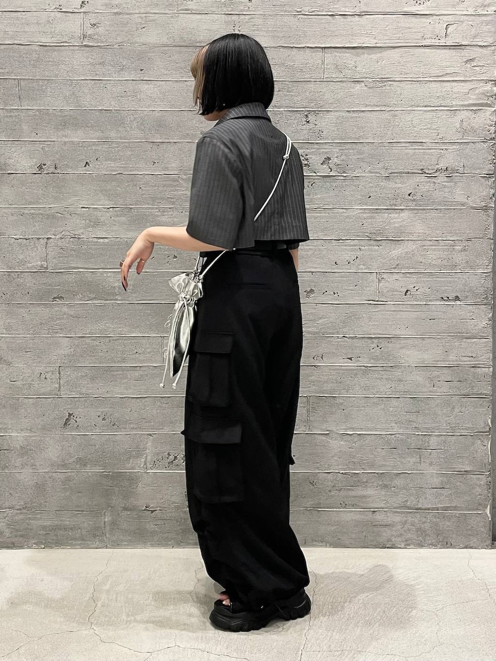 グレー系のタンクトップ、ブラック系のカーゴパンツ、グレー系のブルゾンを着用したレディースの夏コーディネートの3枚目の写真