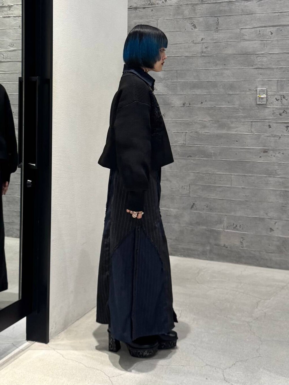 グレー系のブーツ、ブラック系のニット/セーター、ブルー系のスカートを着用したレディースの秋コーディネートの5枚目の写真