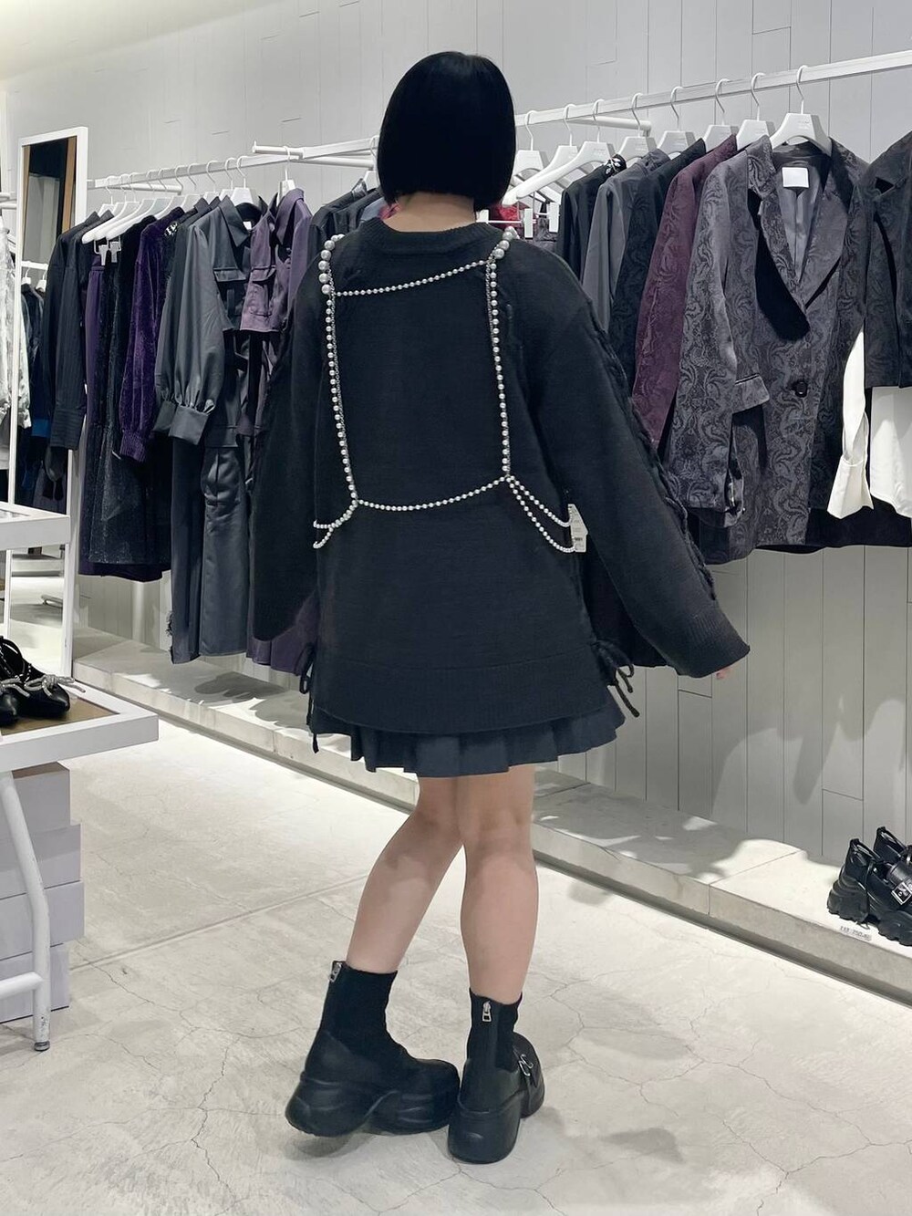 グレー系のテーラードジャケット、ブラック系のブーツ、グレー系のニット/セーターを着用したレディースの秋コーディネートの5枚目の写真