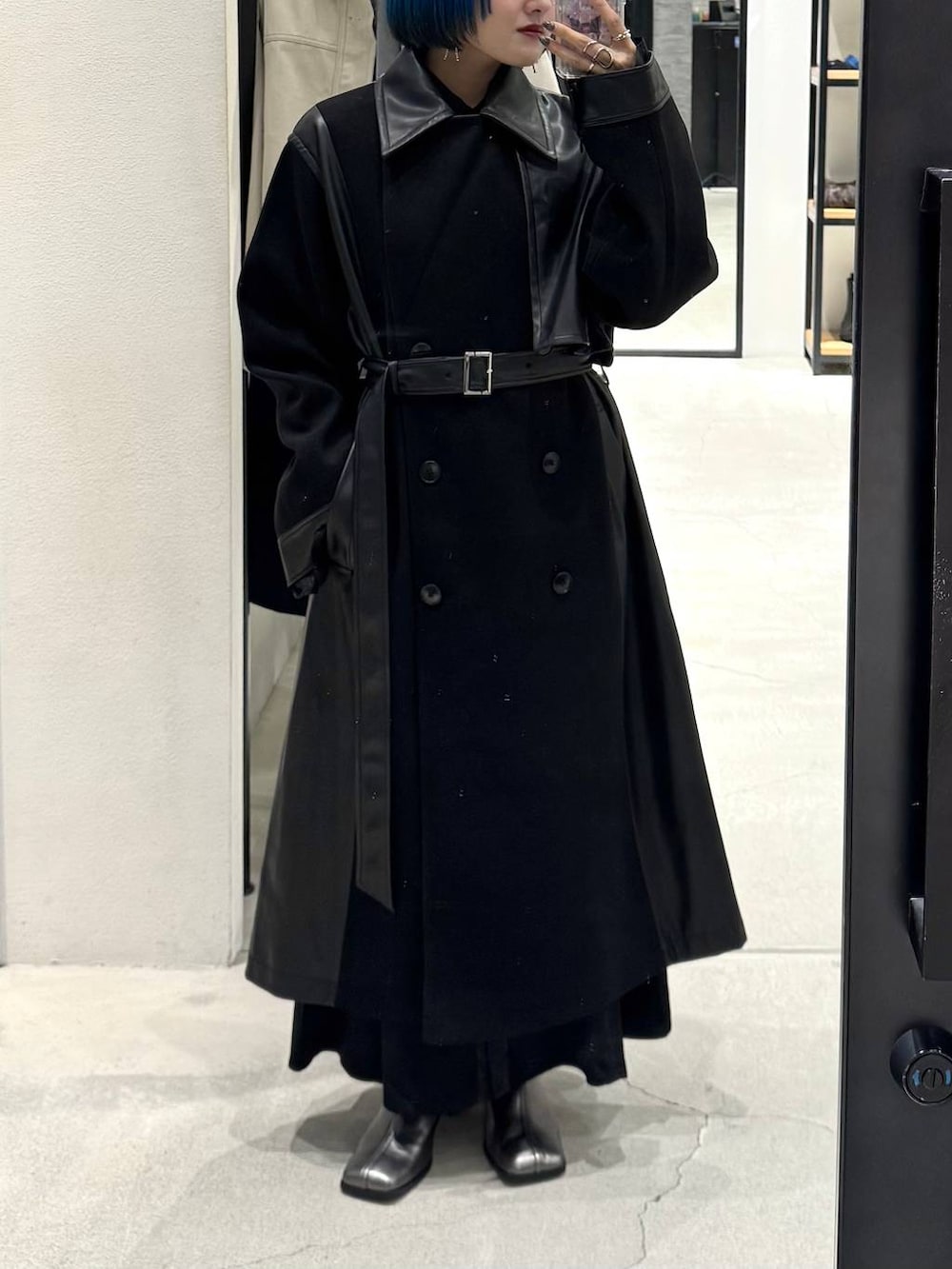 ブラック系のチェスターコート、シルバー系のブーツ、ブラック系のワンピースを着用したレディースの秋コーディネートの3枚目の写真