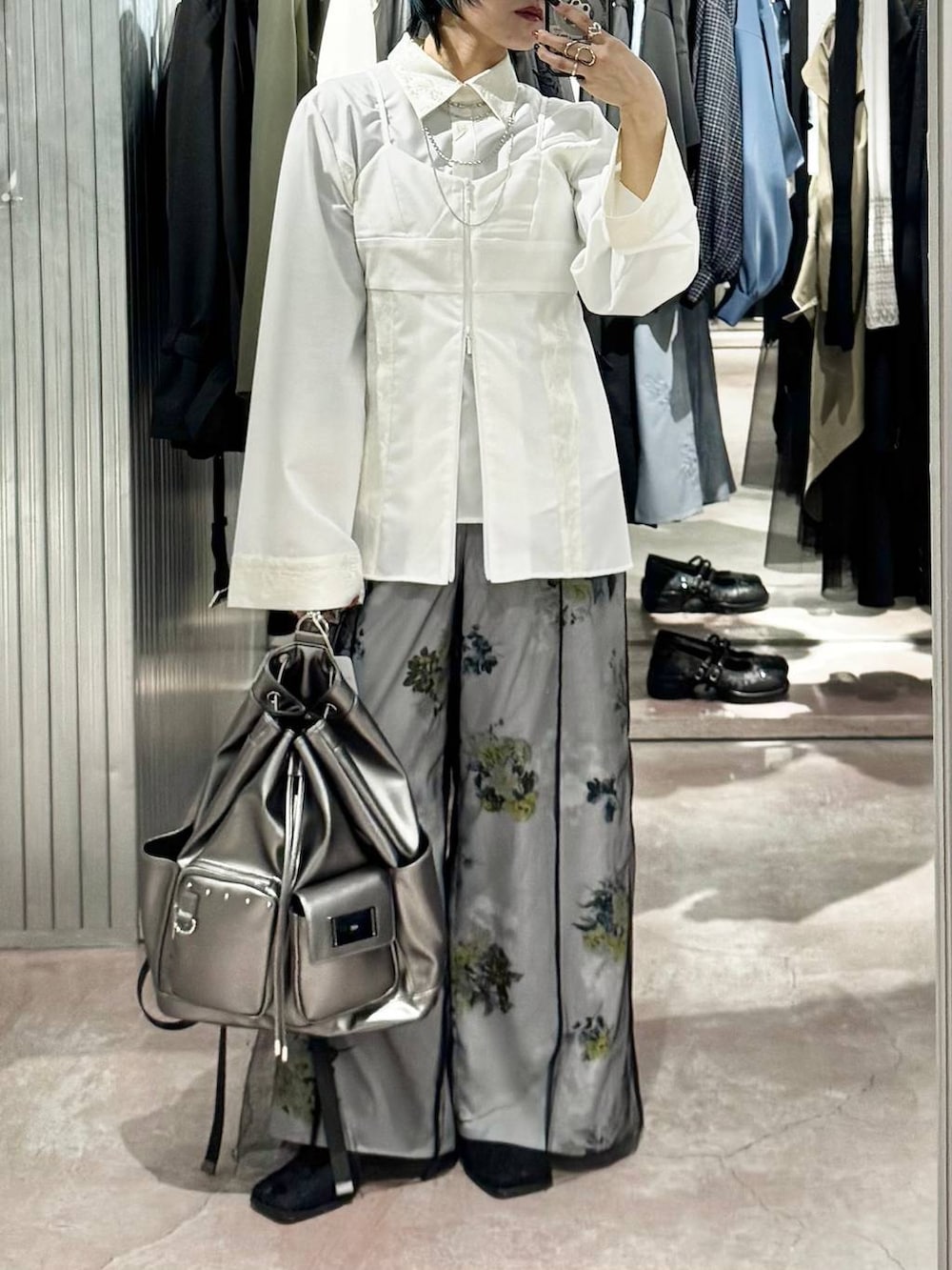 シルバー系のバックパック/リュック、ブラック系のブーツ、ホワイト系のシャツ/ブラウスを着用したレディースの春コーディネートの2枚目の写真