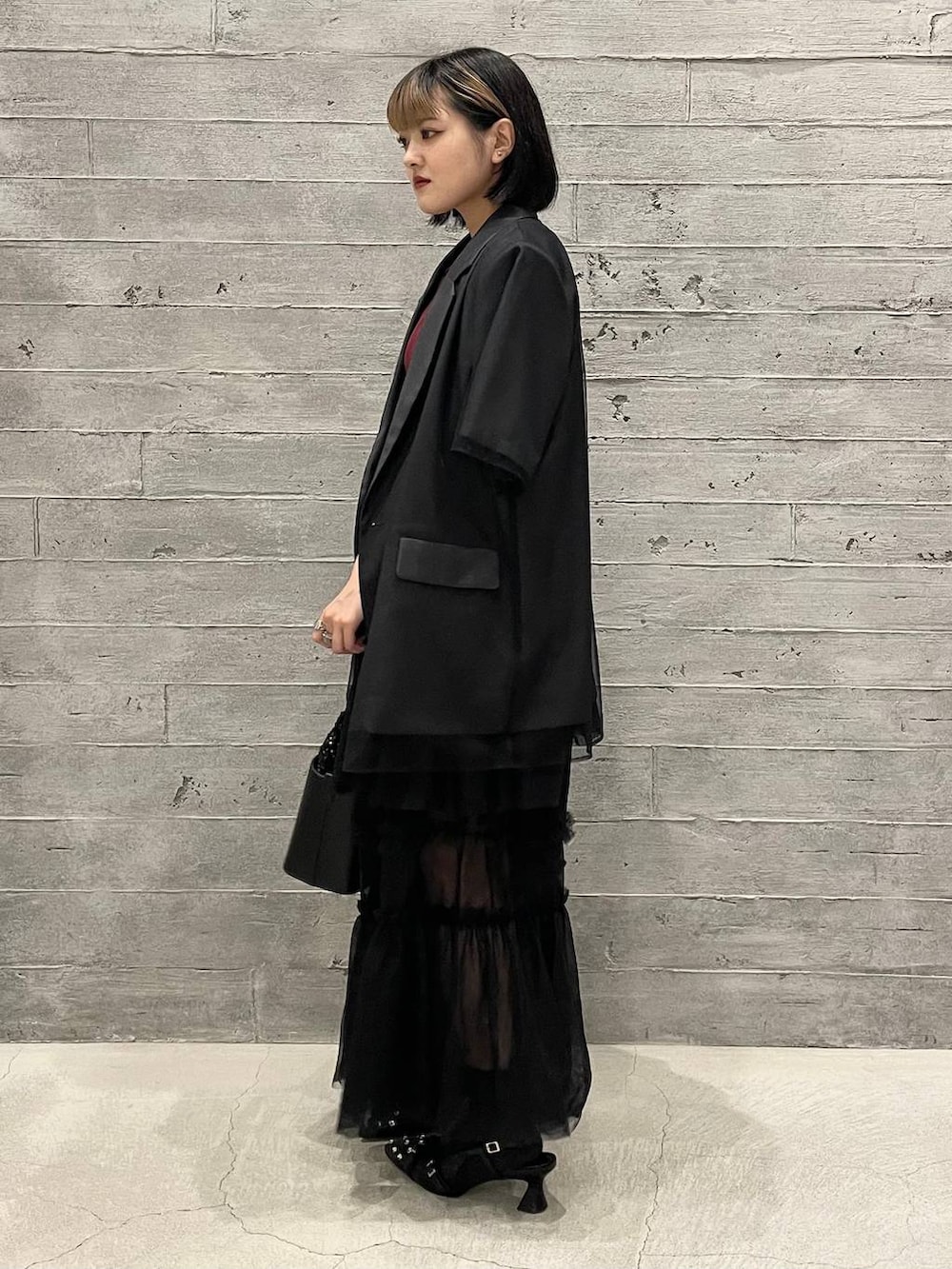 レッド系のニット/セーター、ブラック系のショルダーバッグ、ブラック系のパンプスを着用したレディースの夏コーディネートの4枚目の写真