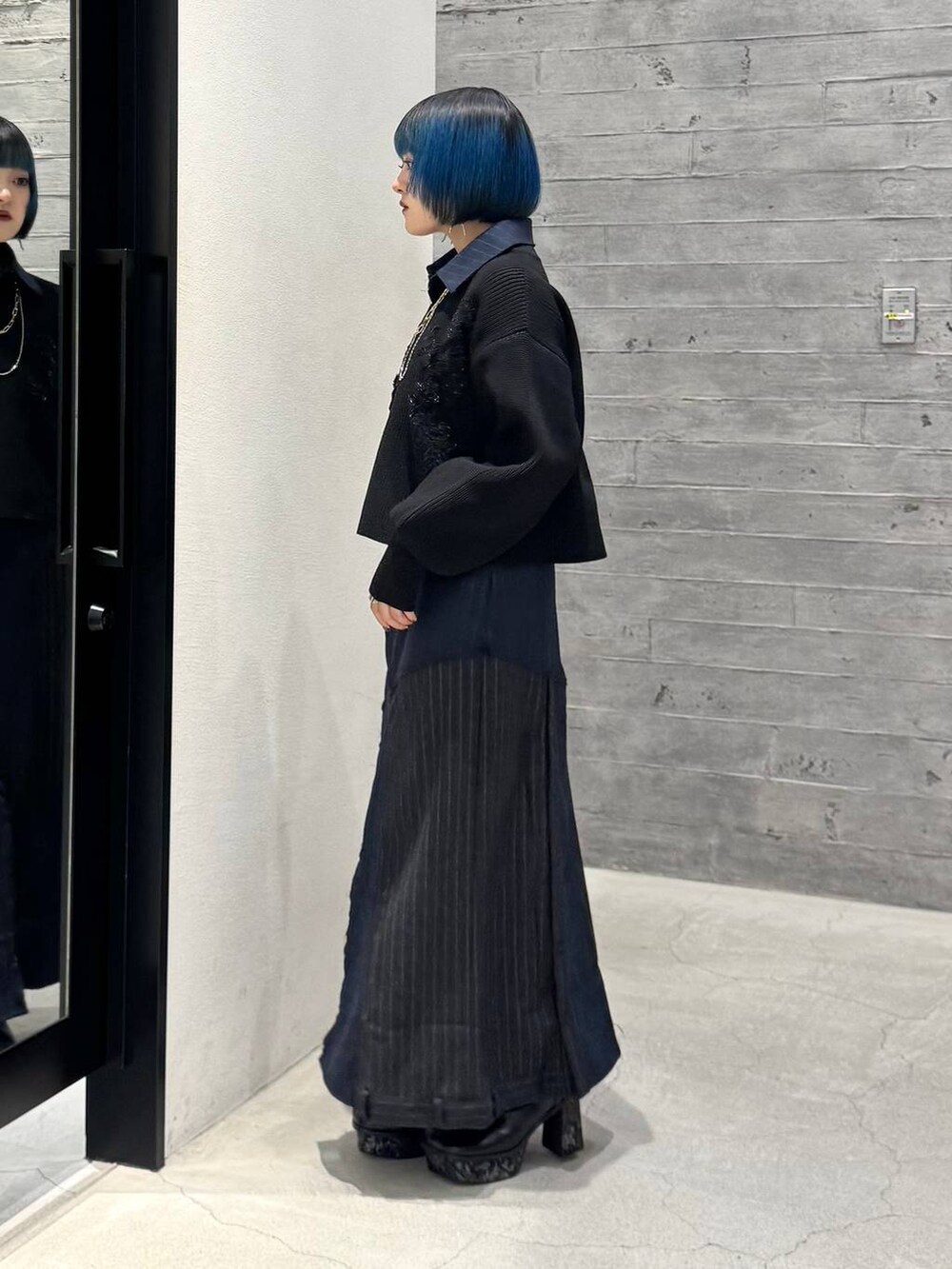 グレー系のブーツ、ブラック系のニット/セーター、ブルー系のスカートを着用したレディースの秋コーディネートの3枚目の写真