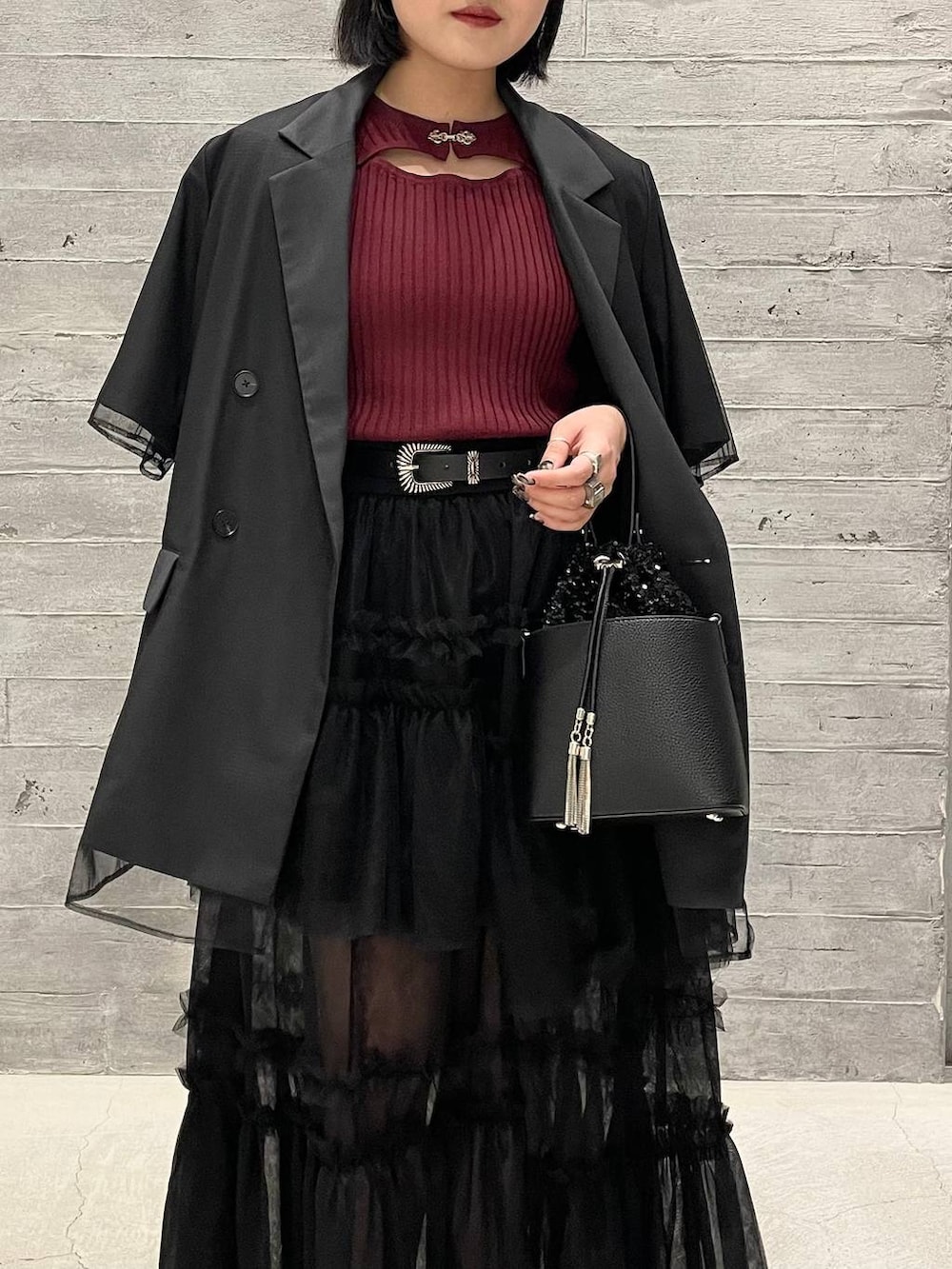 レッド系のニット/セーター、ブラック系のショルダーバッグ、ブラック系のパンプスを着用したレディースの夏コーディネートの2枚目の写真