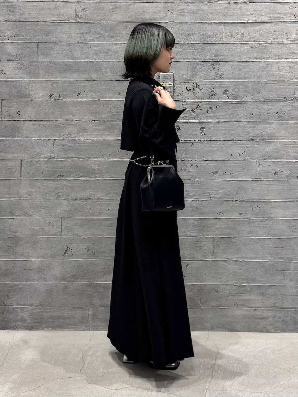 シルバー系のブーツ、ブラック系のワンピース、ブラック系のショルダーバッグを着用したレディースの秋コーディネートの6枚目の写真