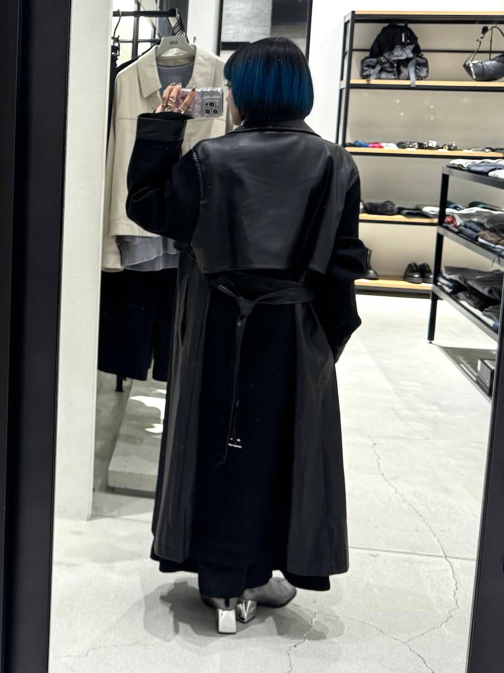 ブラック系のチェスターコート、シルバー系のブーツ、ブラック系のワンピースを着用したレディースの秋コーディネートの6枚目の写真