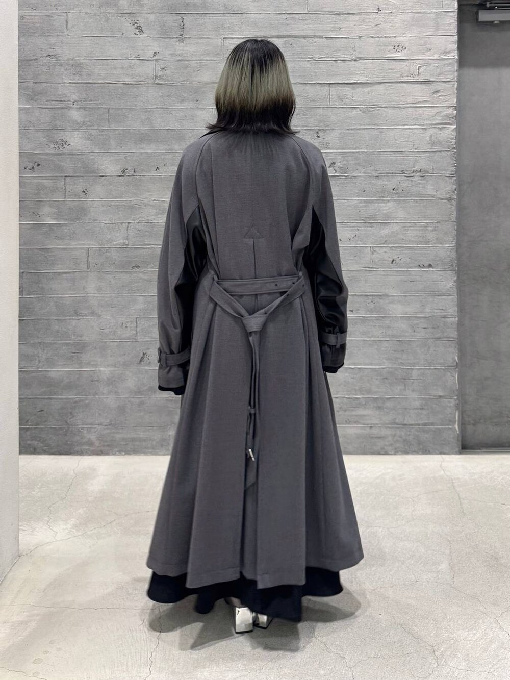 シルバー系のブーツ、グレー系のトレンチコート、ブラック系のワンピースを着用したレディースの秋コーディネートの4枚目の写真