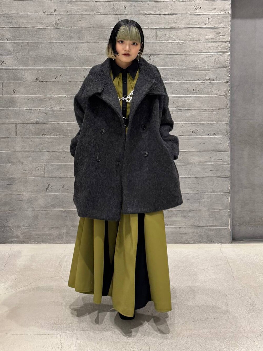 グレー系のブルゾン、ブラック系のブーツ、イエロー系のワンピースを着用したレディースの冬コーディネートの5枚目の写真