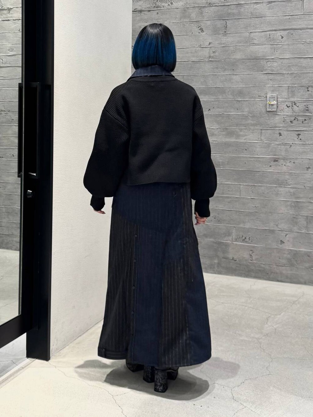 グレー系のブーツ、ブラック系のニット/セーター、ブルー系のスカートを着用したレディースの秋コーディネートの4枚目の写真