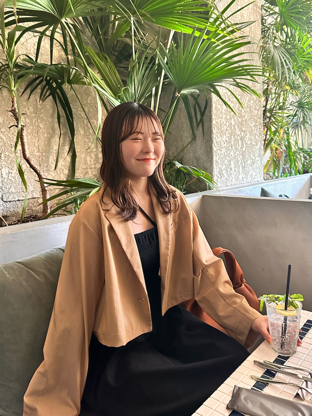 ブラック系のワンピース、オレンジ系のテーラードジャケットを着用したレディースの夏コーディネートの3枚目の写真