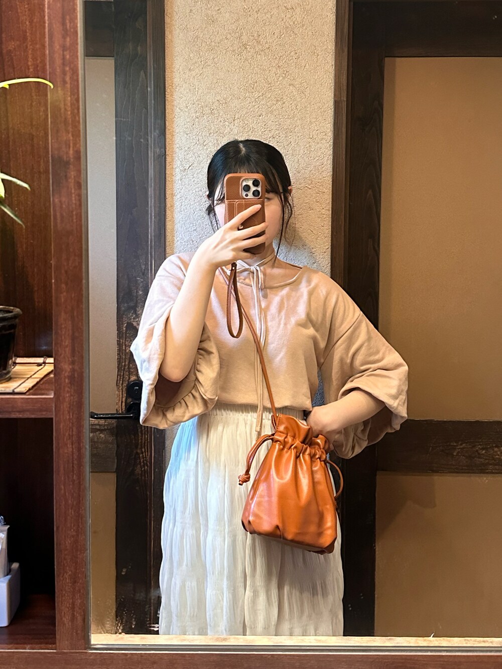 ベージュ系のTシャツ/カットソー、レッド系のショルダーバッグ、ホワイト系のスカートを着用したレディースの夏コーディネートの2枚目の写真