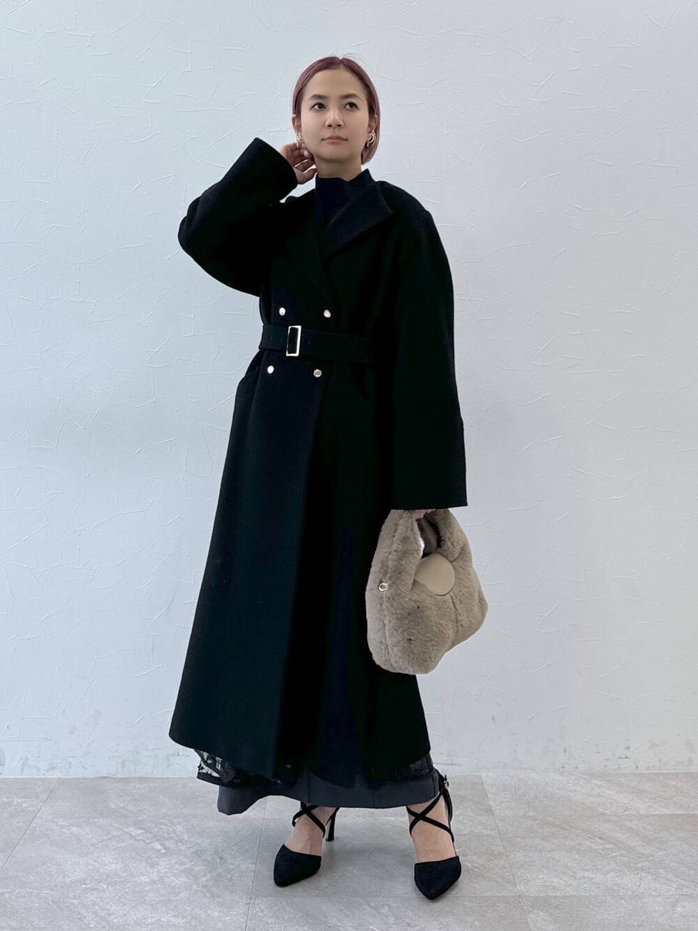 ブルー系のニット/セーター、ブラック系のノーカラーコート、ベージュ系のハンドバッグを着用したレディースの秋コーディネートの2枚目の写真