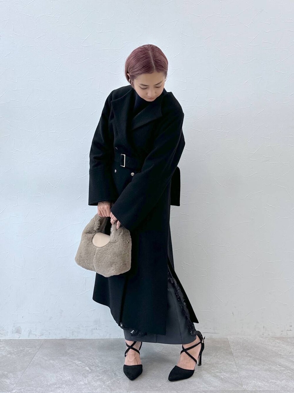 ブルー系のニット/セーター、ブラック系のノーカラーコート、ベージュ系のハンドバッグを着用したレディースの秋コーディネートの3枚目の写真