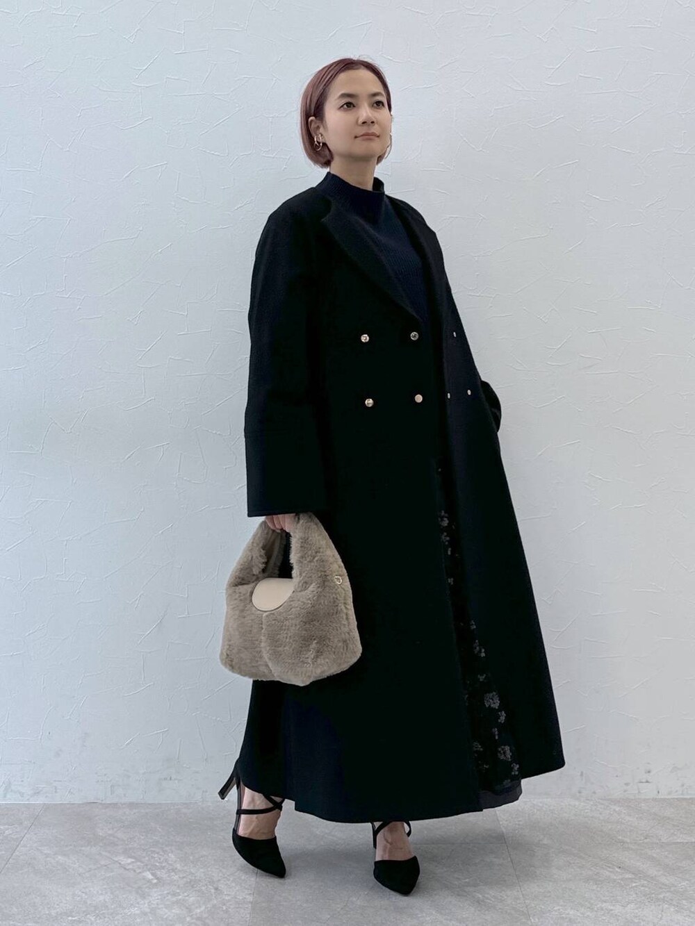 ブルー系のニット/セーター、ブラック系のノーカラーコート、ベージュ系のハンドバッグを着用したレディースの秋コーディネートの7枚目の写真