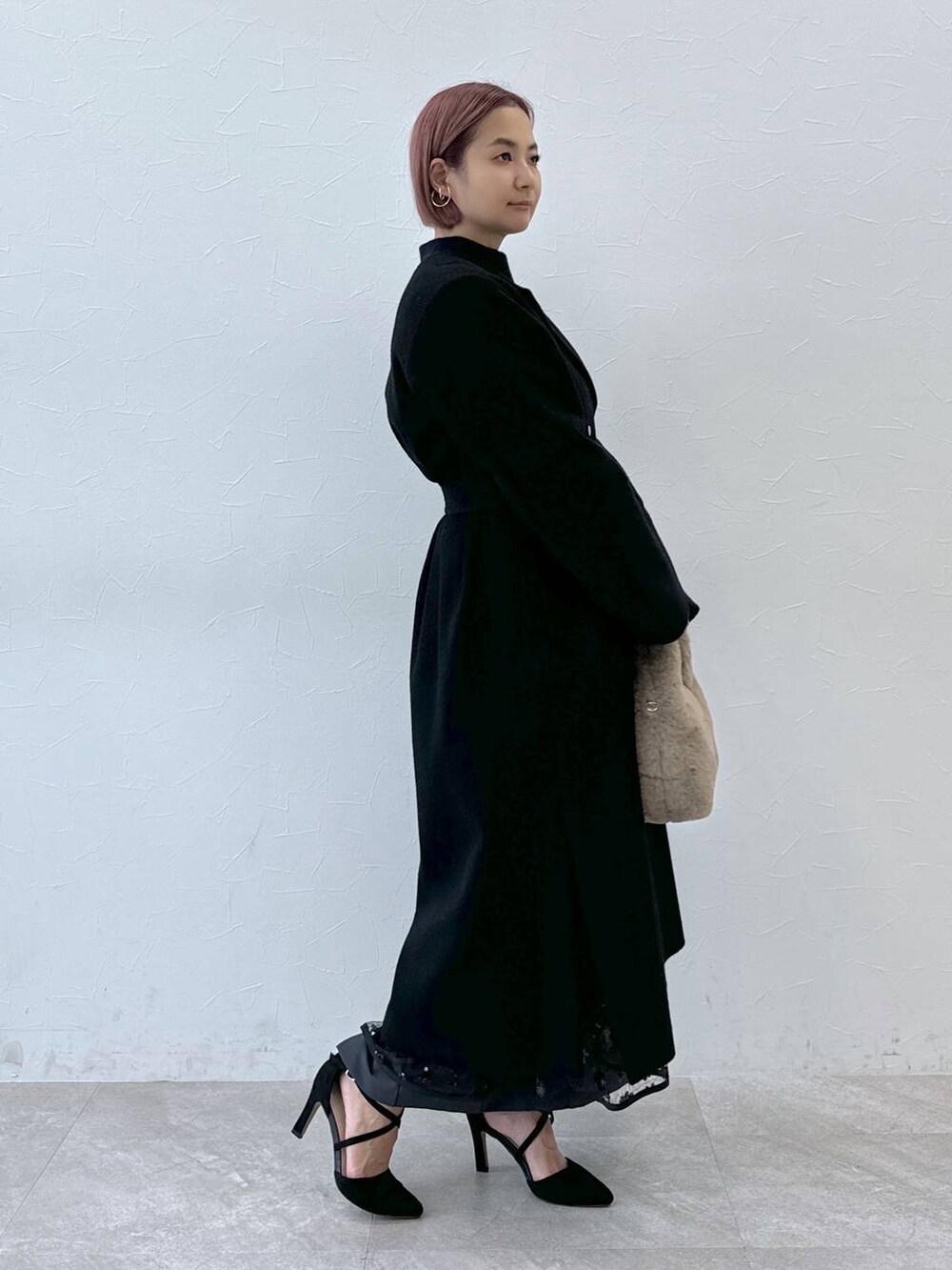 ブルー系のニット/セーター、ブラック系のノーカラーコート、ベージュ系のハンドバッグを着用したレディースの秋コーディネートの4枚目の写真