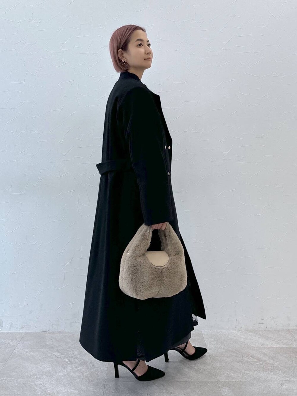 ブルー系のニット/セーター、ブラック系のノーカラーコート、ベージュ系のハンドバッグを着用したレディースの秋コーディネートの8枚目の写真