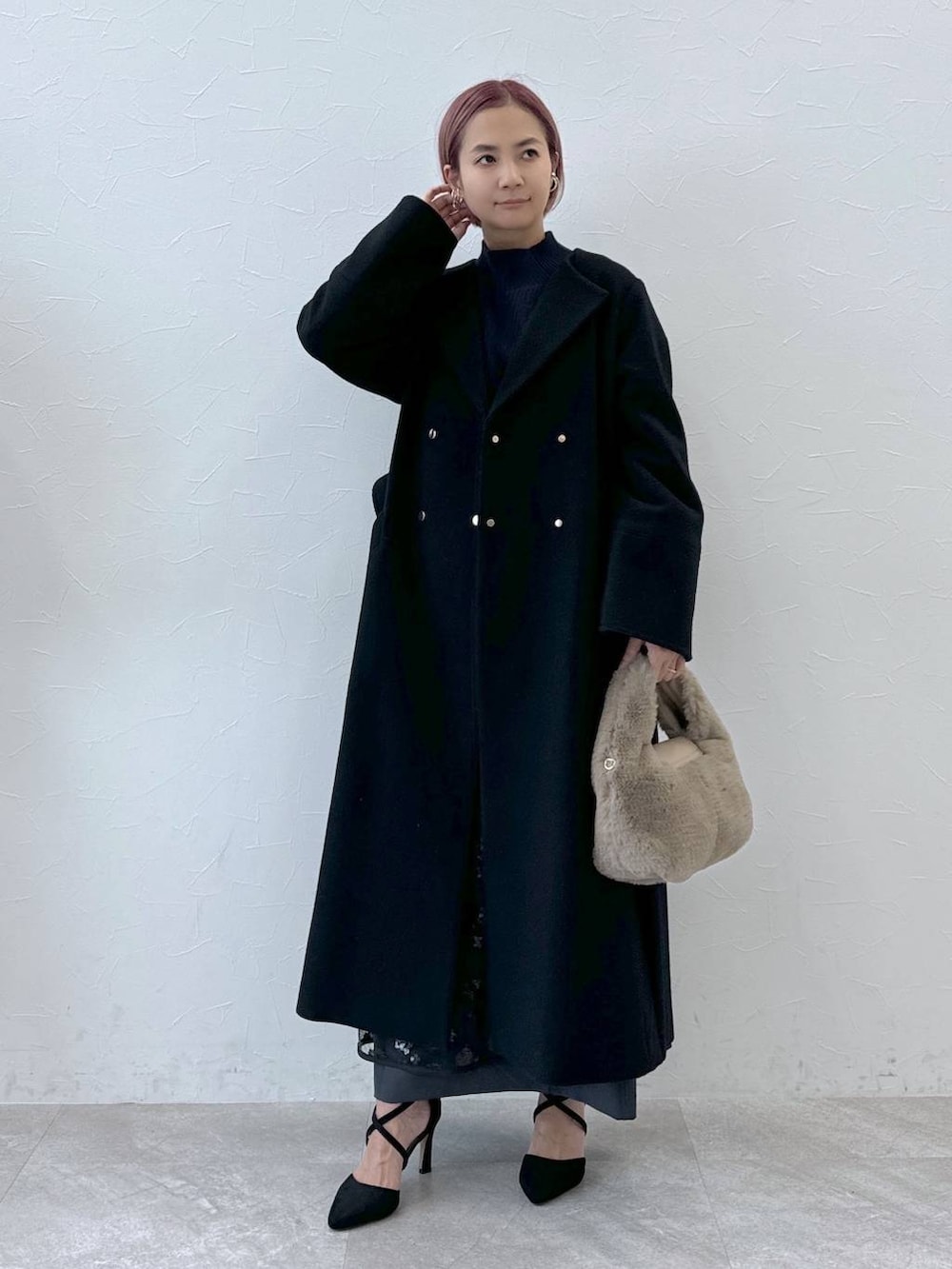 ブルー系のニット/セーター、ブラック系のノーカラーコート、ベージュ系のハンドバッグを着用したレディースの秋コーディネートの5枚目の写真