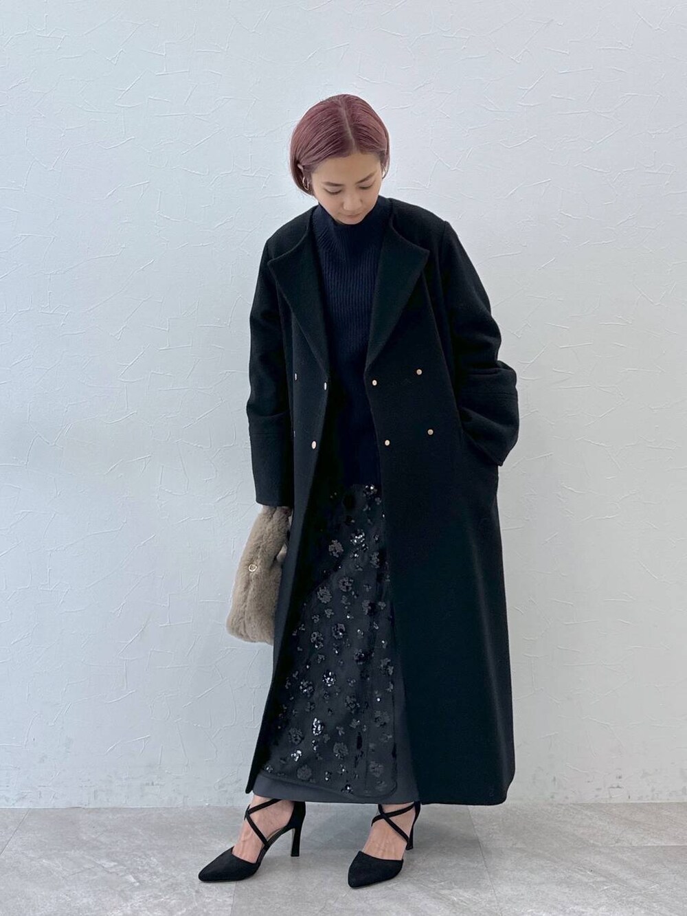 ブルー系のニット/セーター、ブラック系のノーカラーコート、ベージュ系のハンドバッグを着用したレディースの秋コーディネートの6枚目の写真