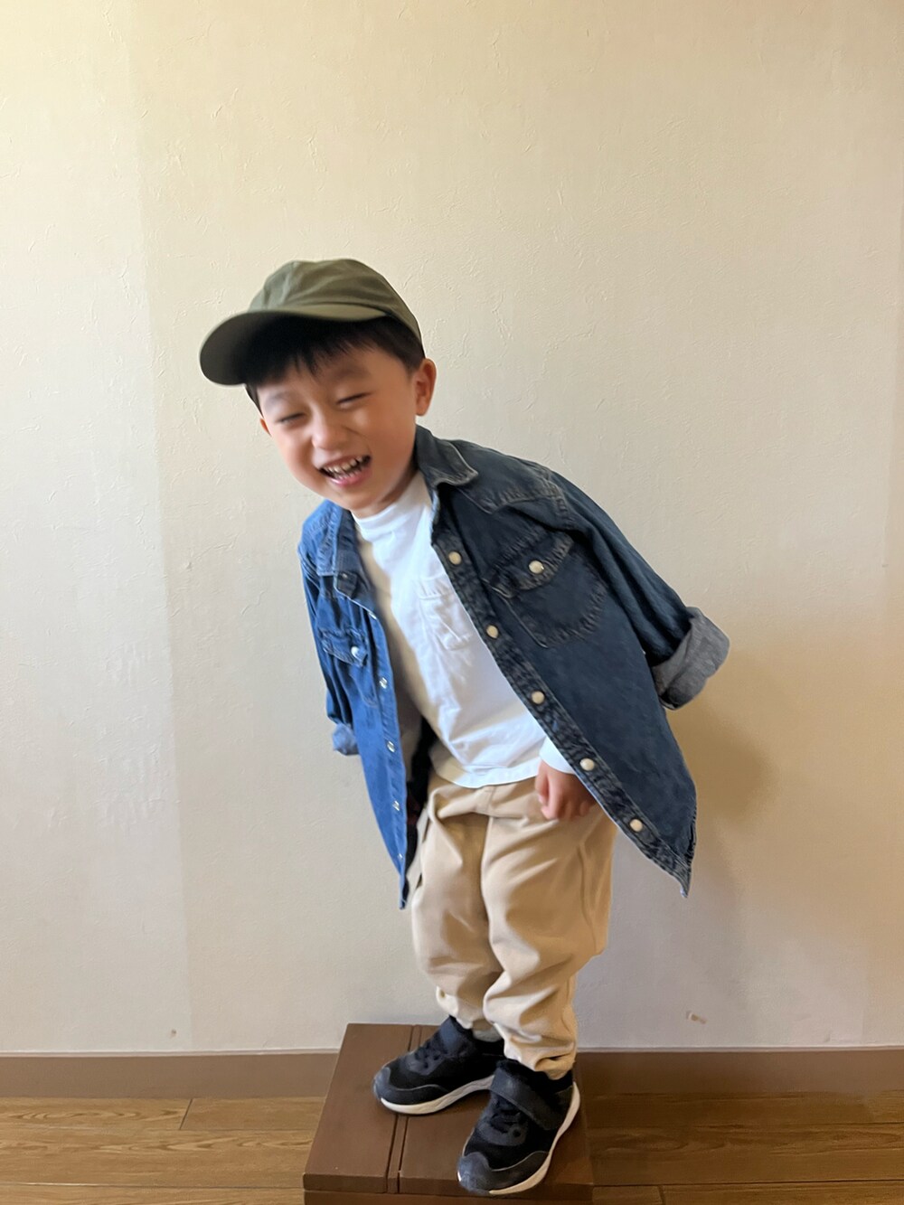 ベージュ系のチノパンツ、ブルー系のデニムジャケット、グリーン系のキャップを着用したキッズの秋コーディネートの2枚目の写真