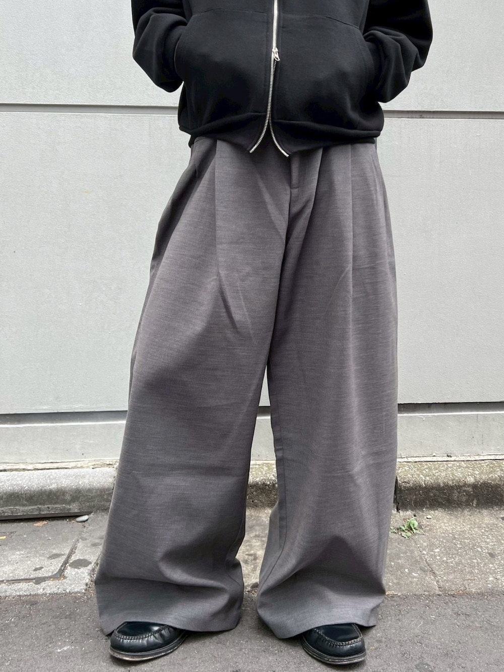 ブラック系のパーカー、グレー系のスラックスを着用したメンズの冬コーディネートの5枚目の写真