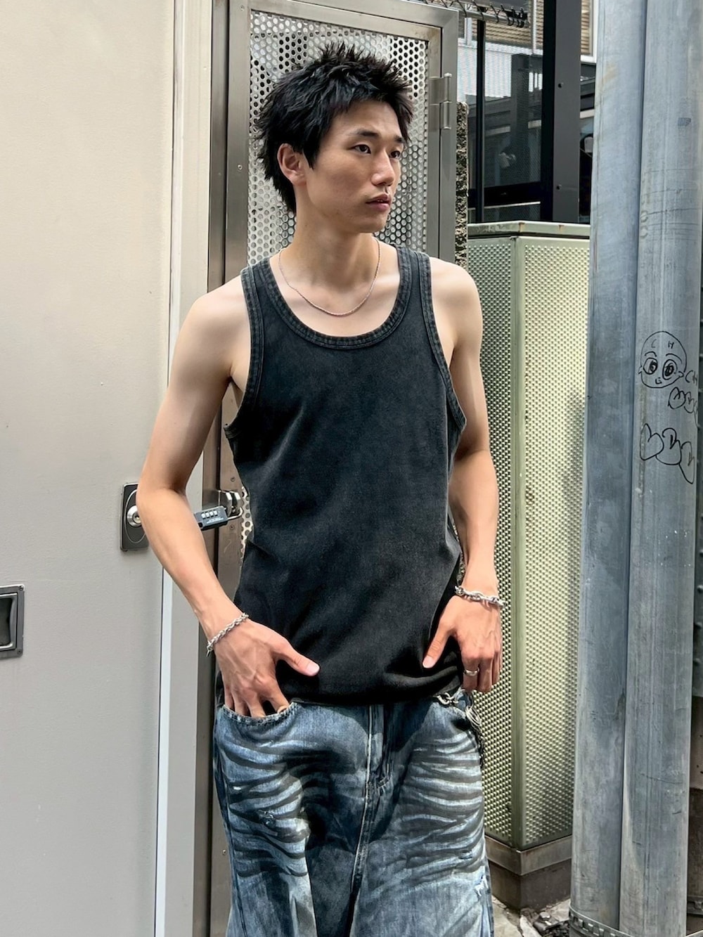 ブラック系のタンクトップ、ブルー系のデニムパンツを着用したメンズの秋コーディネートの3枚目の写真