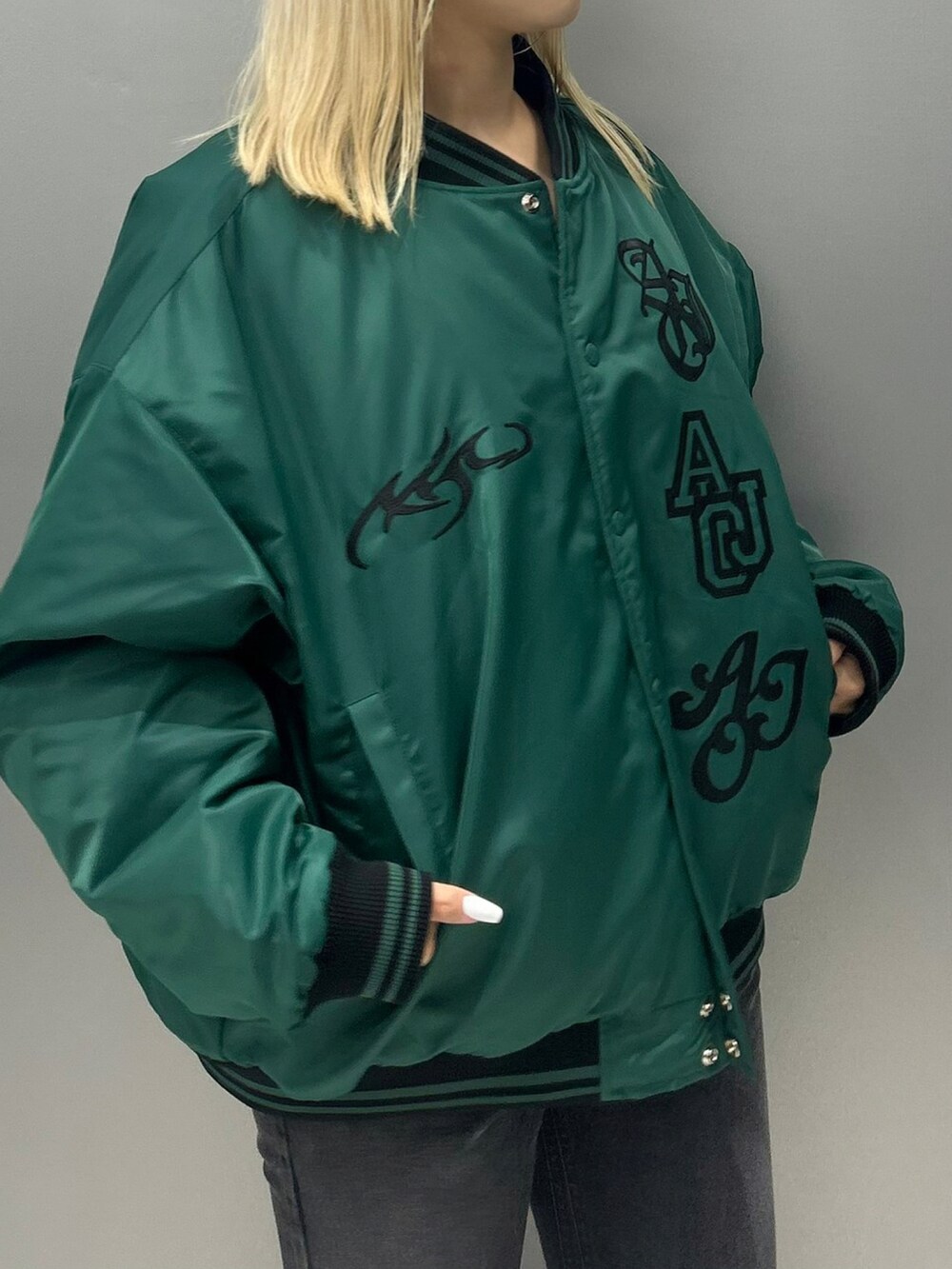 グリーン系のスカジャン、ブラック系のデニムパンツを着用したレディースの秋コーディネートの3枚目の写真