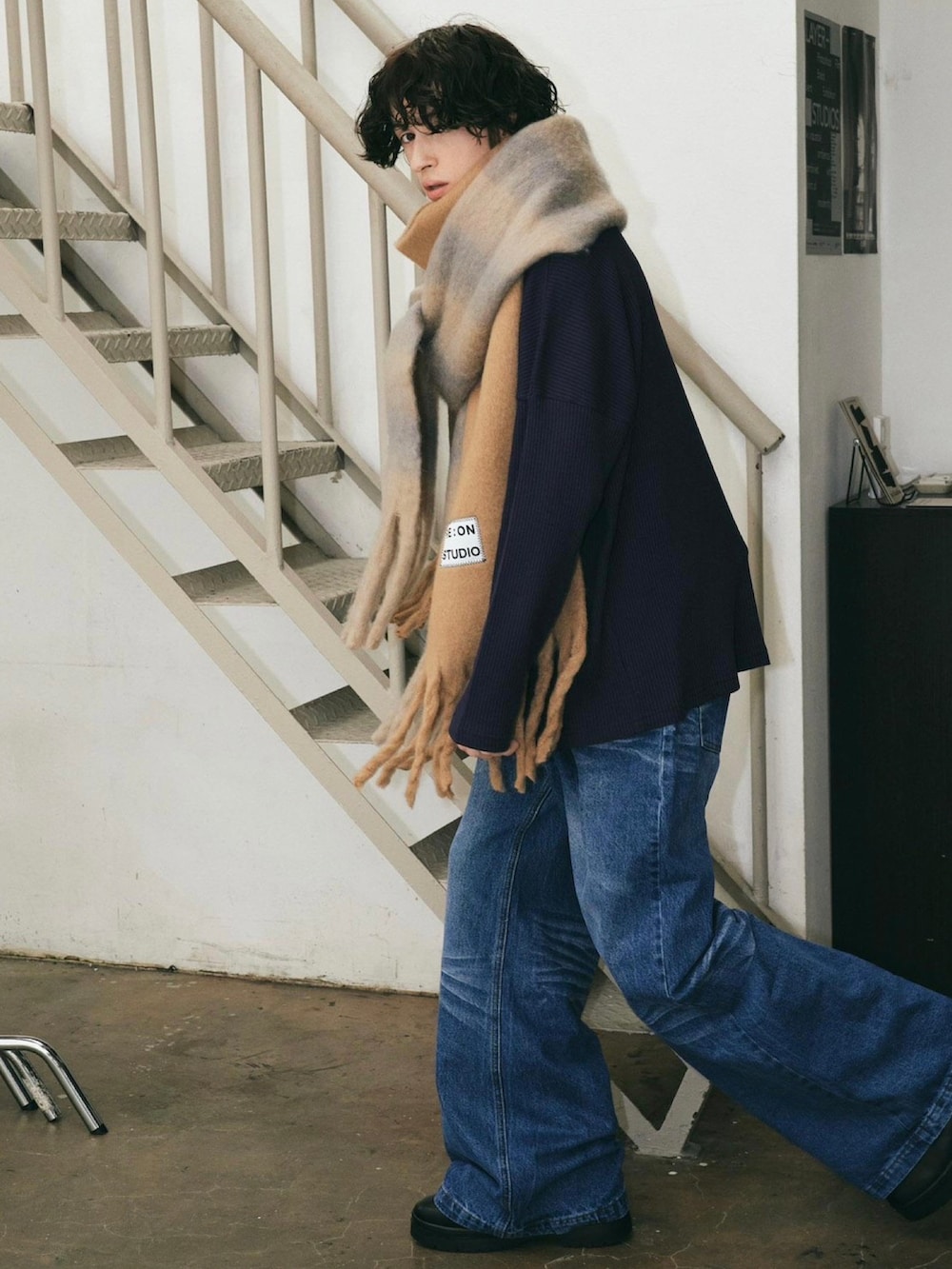 ブラック系のスニーカー、ブルー系のデニムパンツ、ブラウン系のマフラーを着用したメンズの秋コーディネートの2枚目の写真