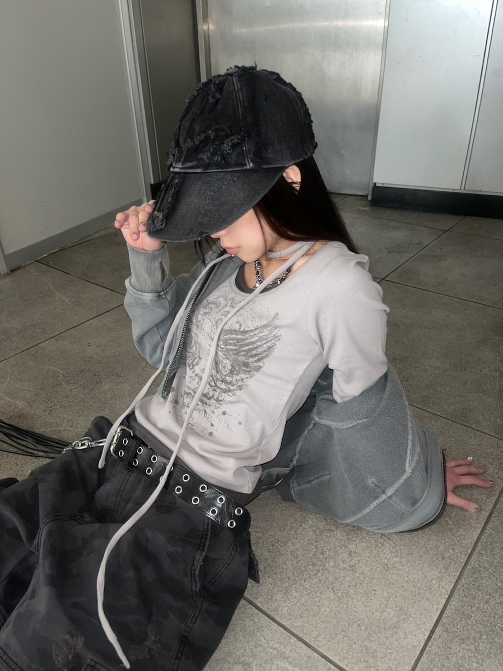 グレー系のTシャツ/カットソー、ブラック系のデニムパンツ、ホワイト系のスニーカーを着用したレディースの春コーディネートの2枚目の写真