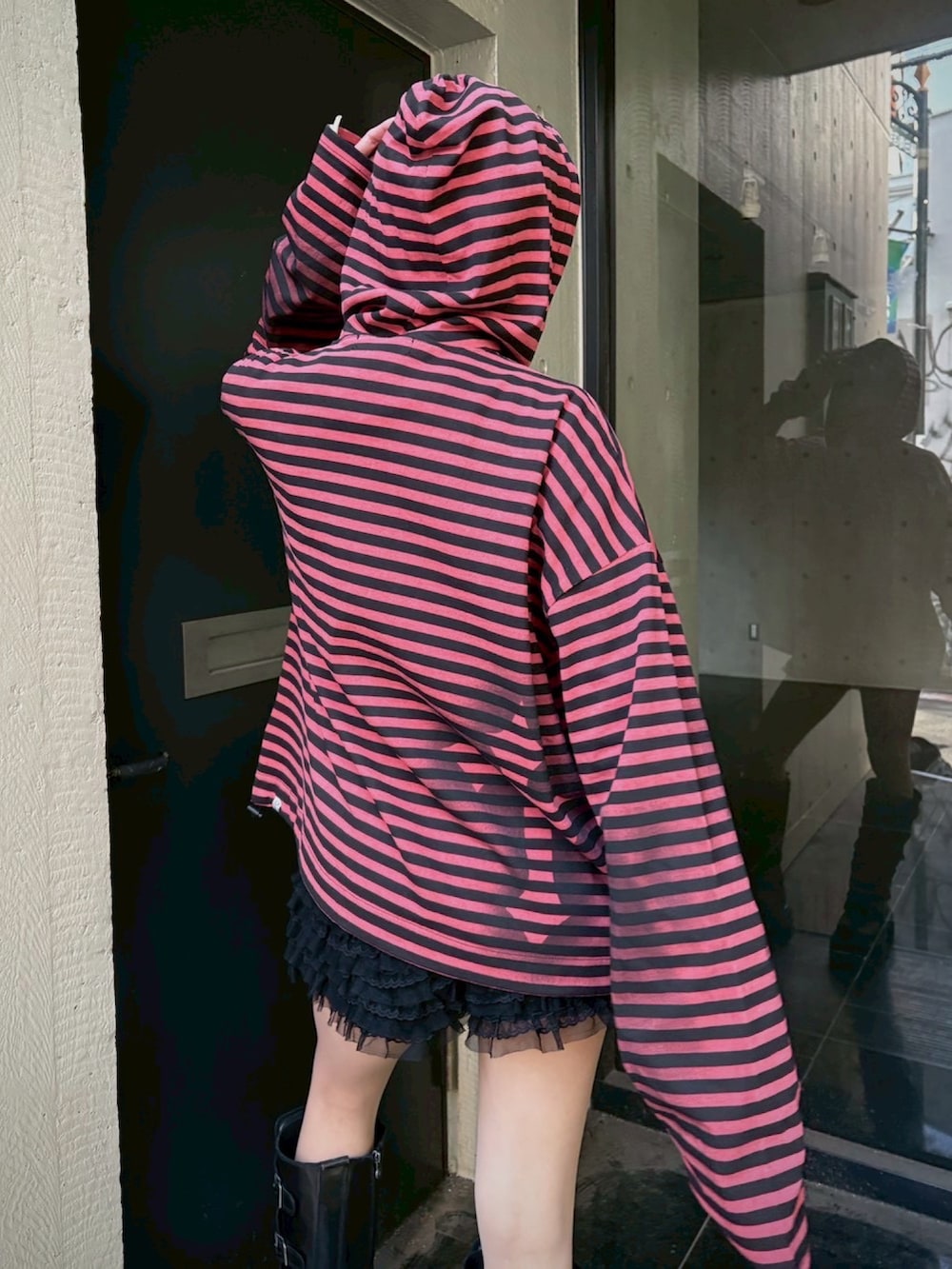 レッド系のパーカー、ブラック系のニットキャップ/ビーニーを着用したレディースの春コーディネートの5枚目の写真