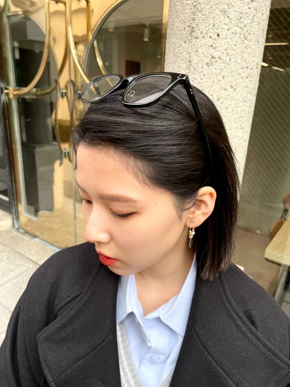 ブラック系のメガネを着用したレディースの冬コーディネートの2枚目の写真