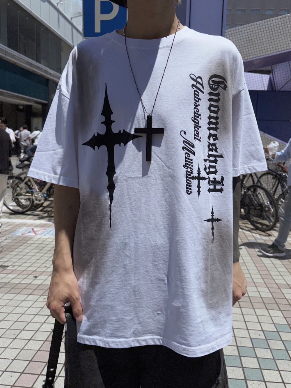 ホワイト系のTシャツ/カットソー、ブラック系のショルダーバッグ、ブラック系のデニムパンツを着用したメンズの夏コーディネートの2枚目の写真