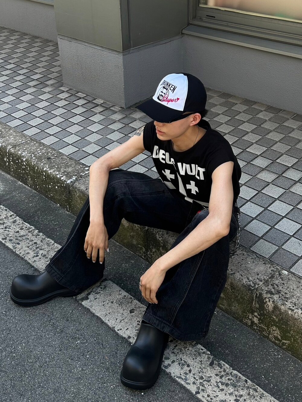 ブラック系のデニムパンツ、ブラック系のスリッポン、ブラック系のキャップを着用したメンズの夏コーディネートの5枚目の写真