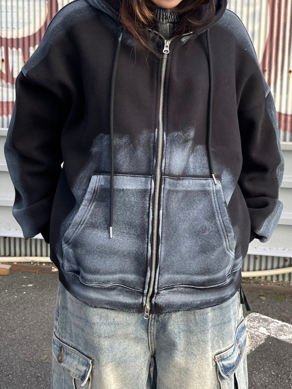 ブルー系のデニムパンツ、ブラック系のニット/セーター、ブラック系のパーカーを着用したレディースの秋コーディネートの4枚目の写真